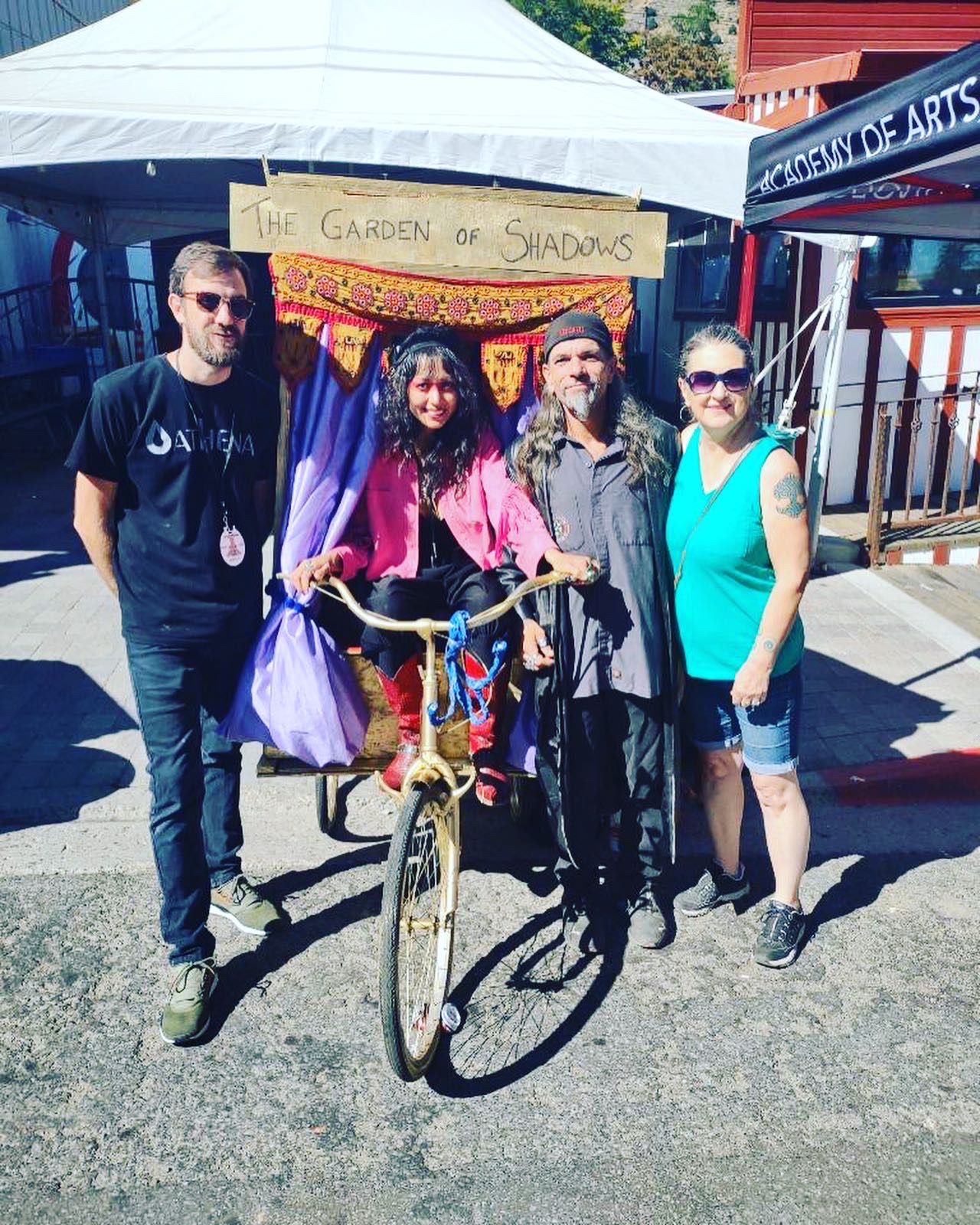 four people and an outhouse on a bike